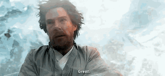 a man with a beard and long hair is standing in front of a mountain and says `` great '' .