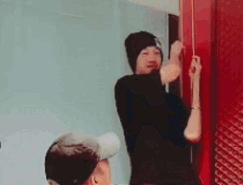 a man in a black hat is standing next to a red door .