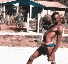 A shirtless person skates outside in an unsteady-looking dance or glide.