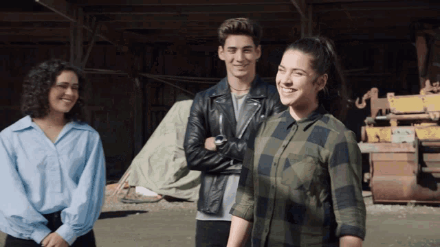 a man in a black leather jacket stands between two women