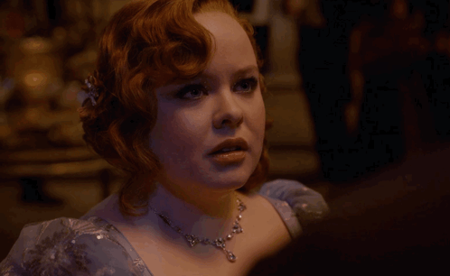a woman with red hair is wearing a blue dress and necklace