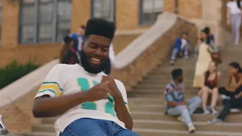 A man sits on outdoor steps and dances with joy.