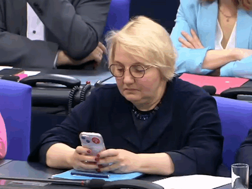 a woman sitting at a table using a cell phone with a sticker on it that says stop
