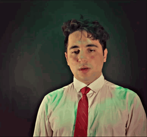 a man in a white shirt and red tie is looking down
