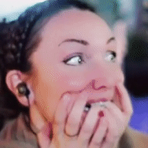 A woman covers her mouth and bites at her nails with anxious eyes.