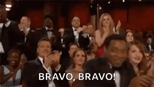 A dressed-up audience claps enthusiastically in a theater, captioned “BRAVO, BRAVO!”