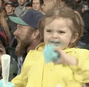 A little girl in a yellow raincoat excitedly waves cotton candy.