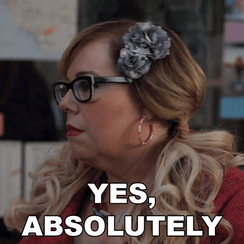 a woman wearing glasses and a flower in her hair says yes , absolutely