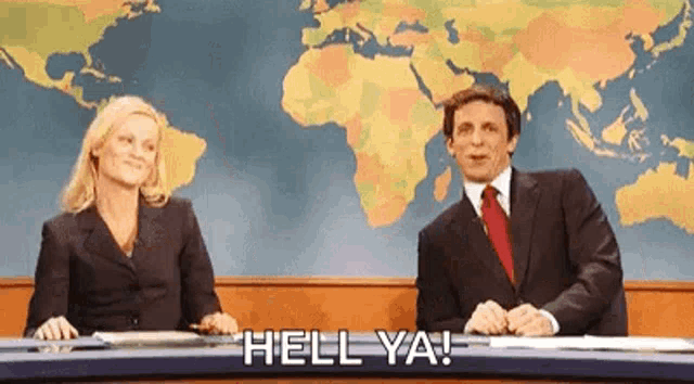 Two news anchors at a desk celebrate beneath the caption “HELL YA!”