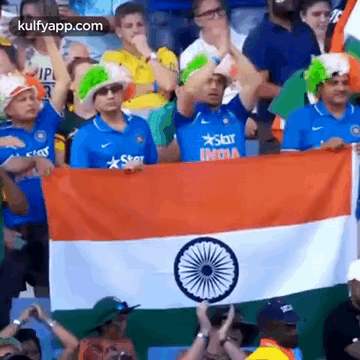 a group of people standing in a stadium holding a flag .