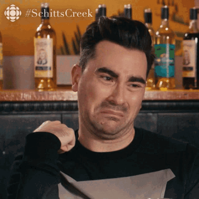 David Rose makes a pained, disgusted face while seated at a bar.