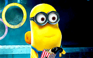 A Minion spits popcorn in surprise at a movie screen.