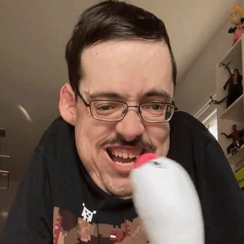 a man with glasses and a mustache is holding a remote control