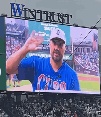 a man in a chicago cubs shirt is on a big screen