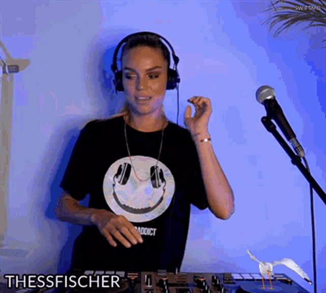 a woman wearing headphones and a t-shirt with a smiley face on it is playing music