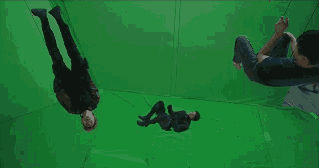 a group of people are hanging upside down in a room on a green screen .