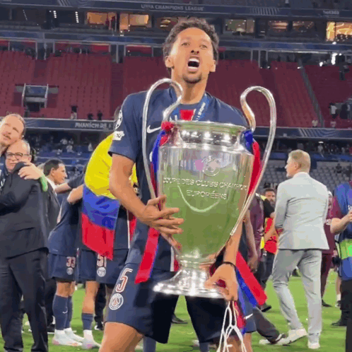 a soccer player holding a trophy that says champions league