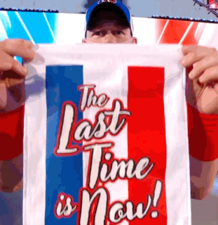 a man holding up a flag that says the last time is now