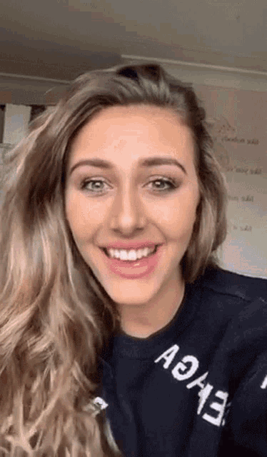 a woman wearing a black shirt with the word achieve on it smiles for the camera