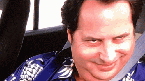 A man leans forward with a mischievous grin.