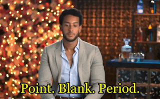 a man in a suit is sitting in front of a christmas tree and the words point blank period are above him