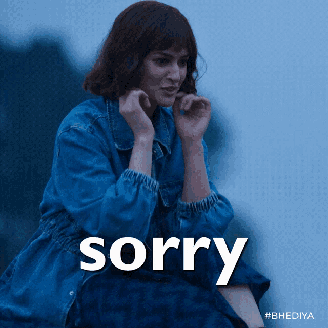 A woman in a blue coat holds her hands up beneath a “sorry” caption.
