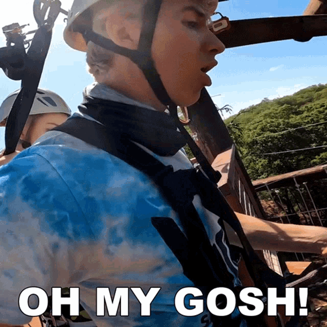 a man wearing a blue tie dye shirt is riding a zip line with the words oh my gosh below him