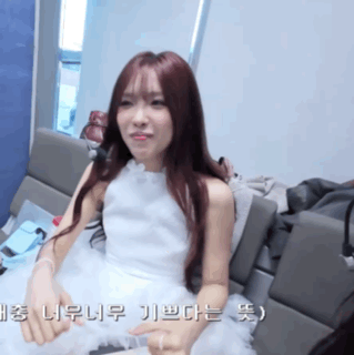 a woman in a white dress is sitting on a couch with foreign writing on the bottom