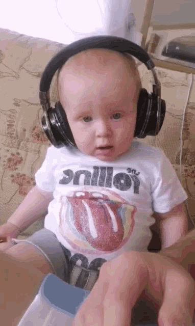 a baby wearing headphones and a shirt that says rolling stones on it