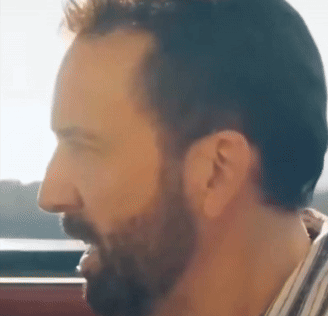 A bearded man looks dazed while riding in a car.