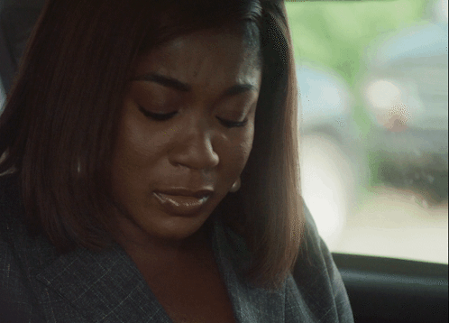 A woman looks down sadly in a car with a shameful expression.