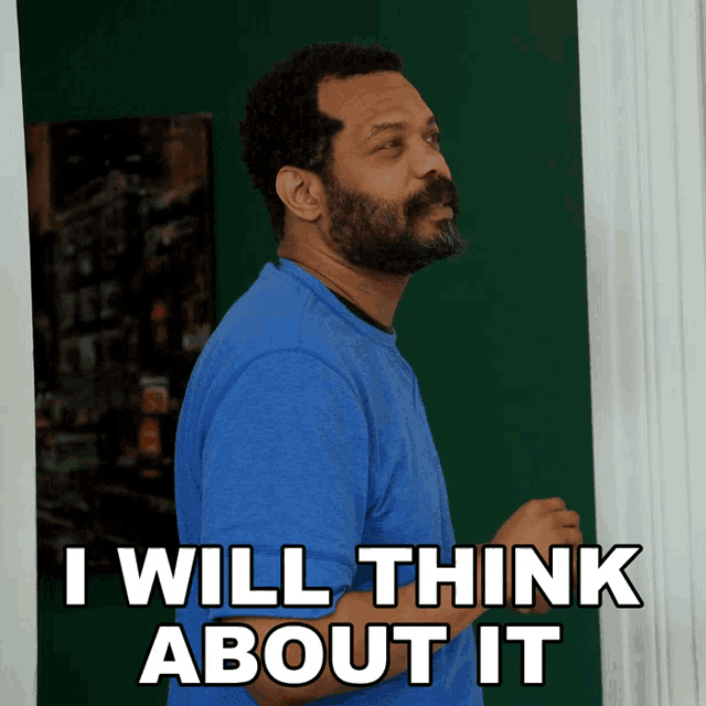 a man in a blue shirt is standing in front of a green wall and says i will think about it