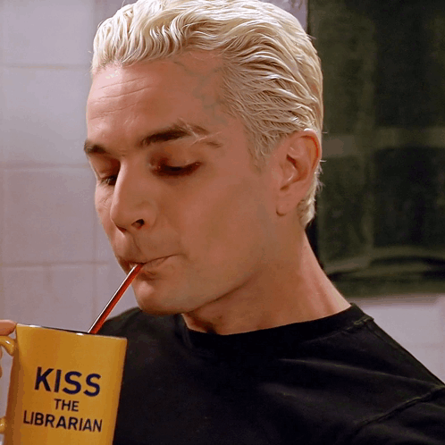 a man is drinking from a yellow cup that says kiss the librarian