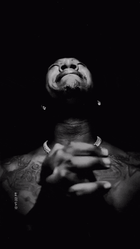 A man clasps his hands and looks upward as if praying emotionally.