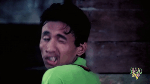 A man makes a comically puckered face in a dark scene.
