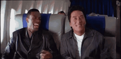 two men are sitting on a plane laughing .