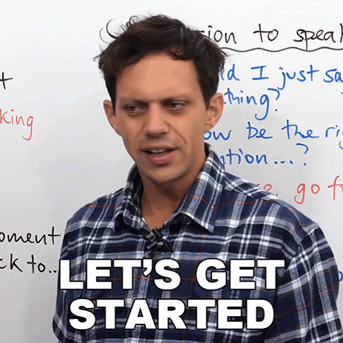 a man in a plaid shirt says let 's get started in front of a white board