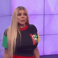 a woman with long blonde hair is wearing a black shirt with a green yellow and red sleeve