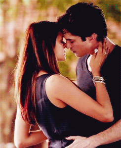 A couple kisses while embracing outdoors.