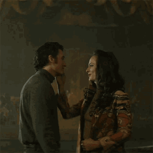 a man and a woman kissing in front of a painting
