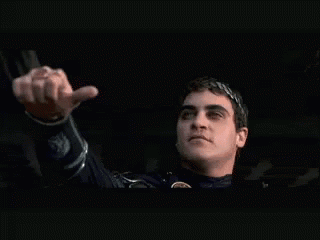 A person in a dark setting gestures with one hand as if offering a choice.