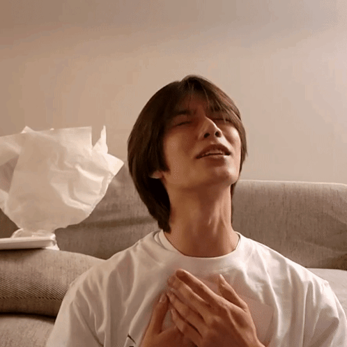 a man in a white shirt is sitting on a couch with his eyes closed