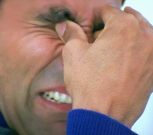 A man pinches his face while appearing to fake cry.