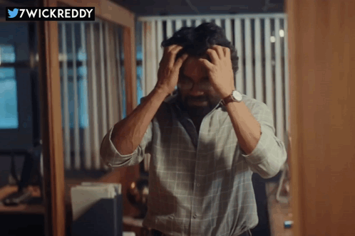 A man grips his head with both hands in a tense, frustrated scene.