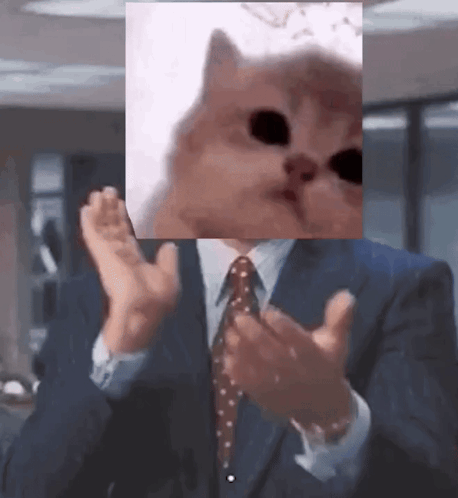 a man in a suit and tie is clapping his hands with a picture of a cat on his face .