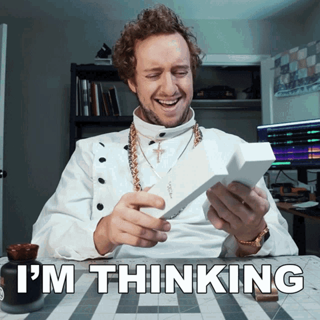 a man sitting at a desk with the words i 'm thinking written below him