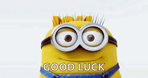 A Minion holds a blue “GOOD LUCK” banner while peeking up from below.