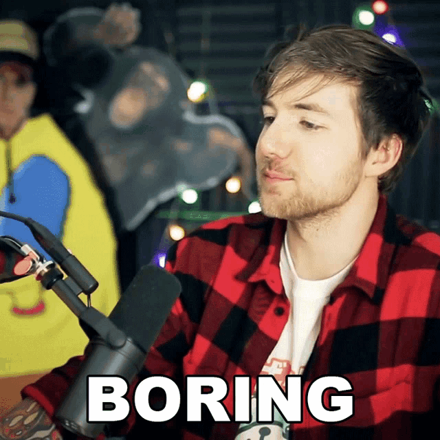 a man in a plaid shirt is sitting in front of a microphone and the word boring is on the bottom