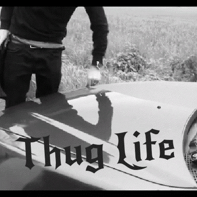 a black and white photo of a man kneeling on the hood of a car with the word thug life written on it .