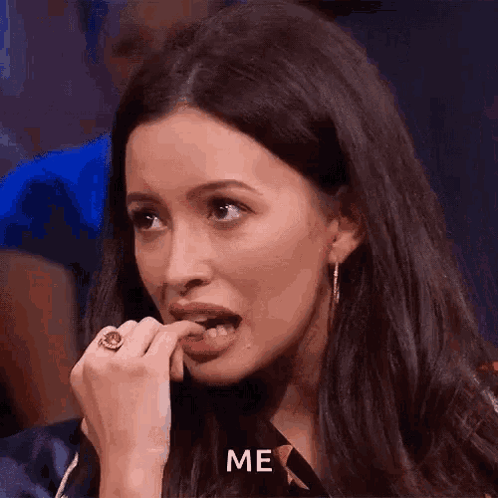 A woman bites her fingernail and looks offscreen nervously.